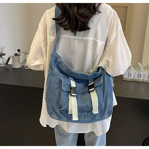 Detail of blue denim messenger bag with buckle pockets and frayed edge texture