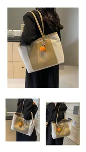 Detail of canvas tote bag with contrast pocket and knit orange fruit charm accessory