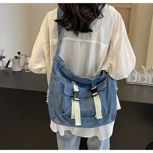 Detail of blue denim canvas crossbody bag with fringe edges and utility buckles