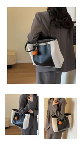 Detail of canvas tote bag with black leather trim and cute orange knit charm