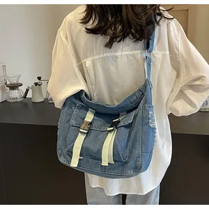 Detail of blue denim crossbody bag featuring white straps and frayed edges for retro style