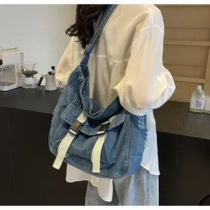 Detail of blue denim messenger bag with off-white straps and trendy frayed edge tassels