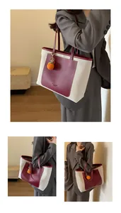 Detail of canvas tote bag with burgundy leather trim and woven orange pendant