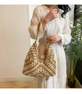 Close-up of hand-woven straw hobo bag with hollow texture and brown leather strap