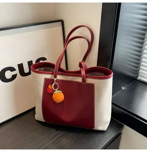 Detail of canvas tote bag with burgundy leather trim and hand-woven fruit charm