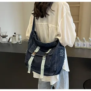 Detail of dark blue denim messenger bag with vintage frayed texture and double front pockets