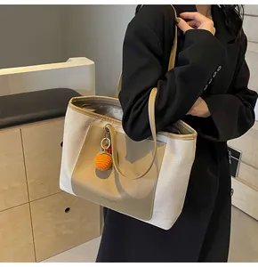 Close-up of minimalist canvas tote bag with leather straps and orange charm decoration