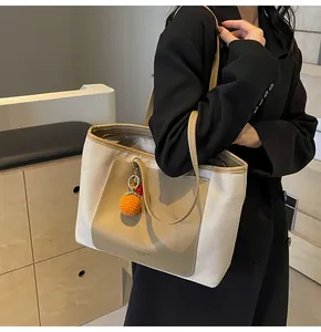 Detail of canvas tote bag with leather trim and decorative orange charm for daily commute