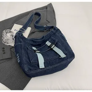 Detail of heavy washed blue denim messenger bag with distressed edges and buckle straps