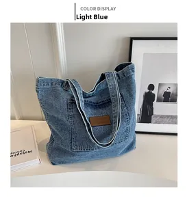 Detail of light blue washed denim tote bag with leather logo patch and outer pocket
