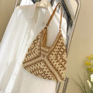 Detailed view of the hollow geometric knit pattern on a straw tote bag with leather strap