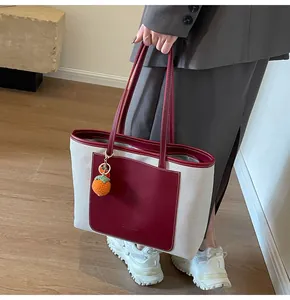 Detail of canvas tote bag with red leather trim and orange knitted fruit charm