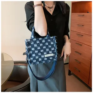 Close-up of blue checkerboard denim tote bag featuring distressed frayed edges and strap
