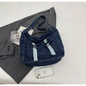 Detail of dark blue denim messenger bag with light blue straps and black buckles