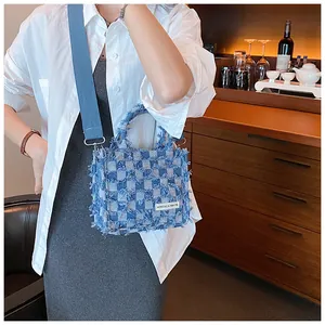 Detail of plaid denim tote bag featuring fringe edges and adjustable crossbody strap