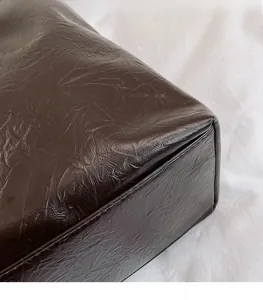 Gros plan sur le cabas en similicuir marron foncé plissé avec détails de couture