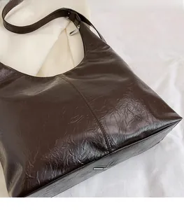 Vue macro du sac hobo café foncé montrant la texture du cuir plissé et le style minimaliste