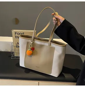 Detail of canvas and leather tote bag featuring brand logo and orange knit charm