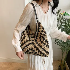 Detail of handwoven straw tote bag with black and yellow geometric pattern on model
