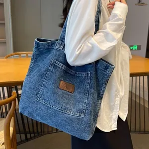 Washed denim tote bag with brown leather patch on shoulder showing large capacity