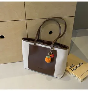 Detailed shot of canvas tote bag with brown leather pocket and orange knitted charm