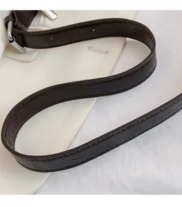 Détail de la bandoulière réglable en cuir marron foncé avec boucle argentée et texture fine