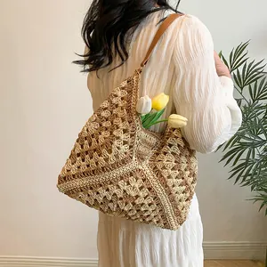Detailed close-up of a handmade crochet straw tote bag with brown leather shoulder straps