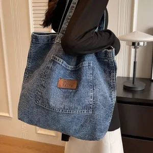 Deep blue washed denim tote bag with brown leather patch on a stylish shoulder strap