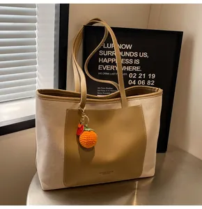 Detail of canvas tote bag with khaki leather pocket and orange knit fruit charm