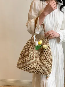 Close-up of hollow crochet straw bag featuring leather handles and delicate wood bead detail