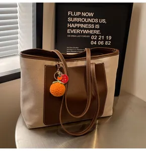 Detail of canvas tote bag with brown leather pocket and a cute orange fruit charm