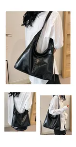 Détail d'un grand sac cabas noir brillant en forme de croissant avec texture souple et bandoulière