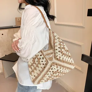 Detailed close-up of woven floral pattern and leather strap on a straw tote bag