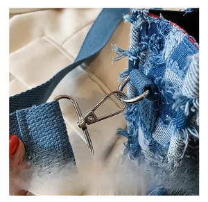 Close-up of silver metal hook and blue denim woven fabric with fringe detail