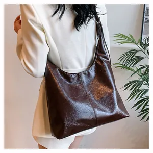 Détail du grand sac cabas en cuir froissé marron foncé sur un blazer blanc élégant