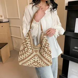 Detail of a handmade straw tote bag featuring geometric knit patterns and a leather strap