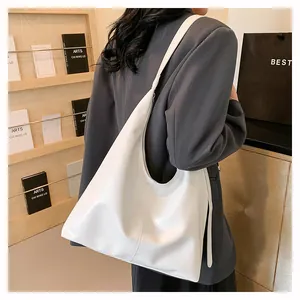 Détail d'un grand sac cabas blanc en cuir texturé porté par un mannequin en décor épuré