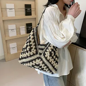 Detail of hand-woven straw tote with black and white geometric crochet pattern