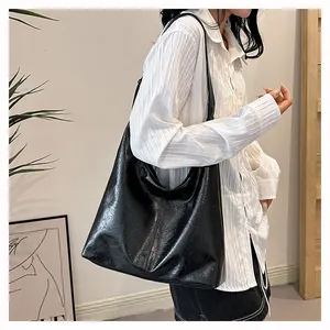 Détail d'un grand sac cabas noir avec une texture de cuir ciré brillant et souple
