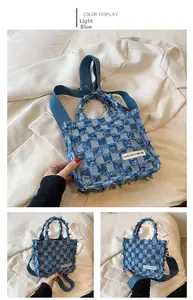 Detail of light blue checkered denim tote bag with frayed edges and wide woven strap
