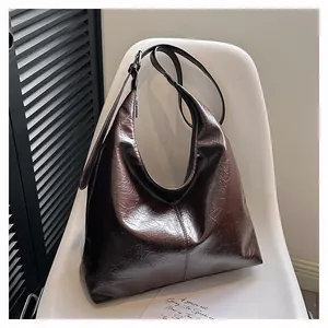 Détail d'un cabas vintage marron foncé avec texture plissée brillante sur chaise blanche