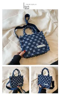 Detailed close-up of dark blue checkered denim tote bag with frayed edges and logo patch