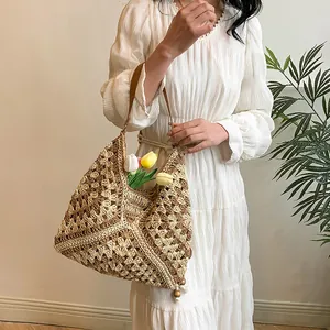 Detail of hand-woven straw tote bag featuring geometric patterns and wooden bead tassels