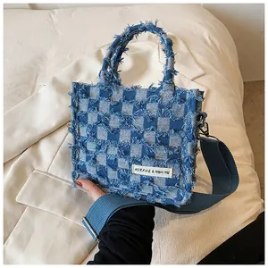 Detailed view of the frayed edge texture on the blue and white checkered denim tote bag