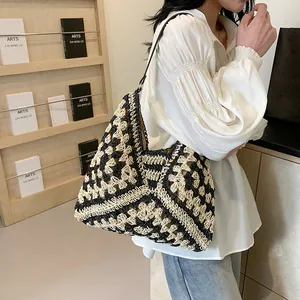 Detail of crochet knit hobo bag featuring black and white geometric weave and leather strap