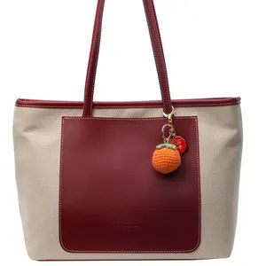 Minimalist bicolor tote bag with beige woven texture and deep red leather front pocket