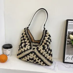 Detail of hand-woven straw tote bag with black and beige geometric patterns and lining