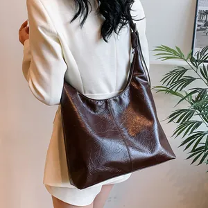 Grand sac cabas marron chocolat en cuir huilé plissé porté par un mannequin en tailleur
