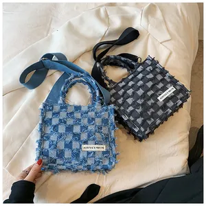 Detail of plaid denim tote bags showing fringed texture and woven shoulder straps