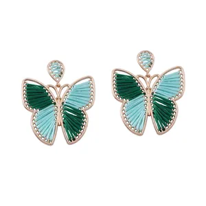 Detalle macro de pendientes de mariposa tejidos a mano con marco de aleación de oro